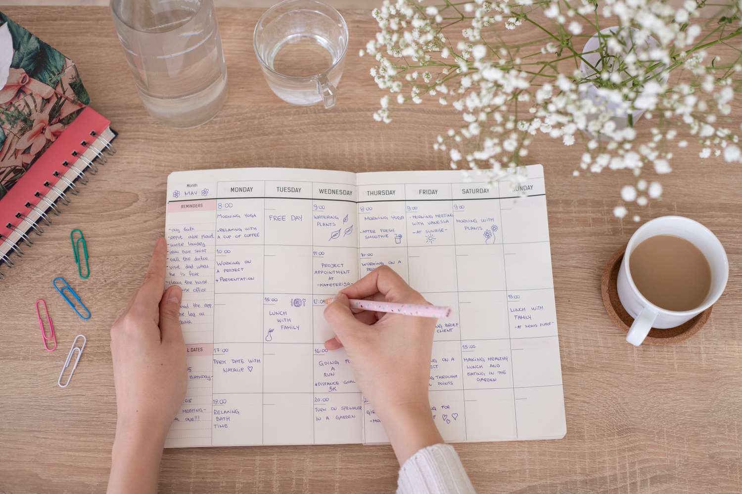Open monthly planner with handwritten goals and a cup of coffee on top